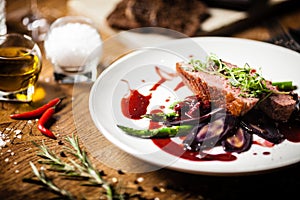 Duck breast with asparagus, salad and sauce on white plate. Delicious healthy grilled and roasted bird fillet food