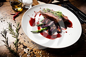 Duck breast with asparagus, salad and sauce on white plate. Delicious healthy grilled and roasted bird fillet food