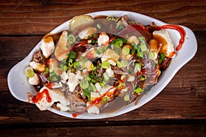 Duck confit poutine dish on wood table