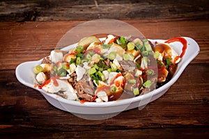 Duck confit poutine dish on wood table photo