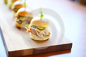 duck confit slider with pickles on a wooden serving tray