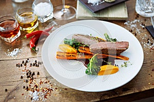 Duck fillet with sweet potato cream, roasted carrots, kale, beet-port sauce on white plate. Grilled and roasted poultry