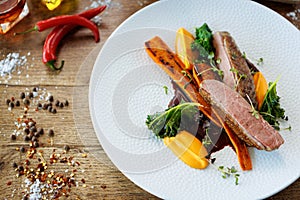 Duck fillet with sweet potato cream, roasted carrots, kale, beet-port sauce on white plate. Grilled and roasted poultry