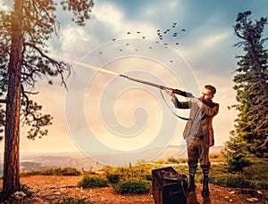 Duck hunter in hunting clothing aims an old rifle photo