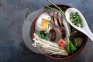 Duck noodles with egg and mushrooms in bowl on dark black stone texture background