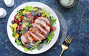 Duck salad with grilled breast with red orange, kumquat, blueberry and chard, frisse, mizuna and arugula leaves on blue table