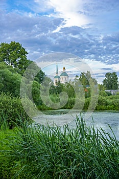 Duckweed covered lake kiovo, moscow region, russia, Orthodox church on the shore overgrown with reeds at summer evening