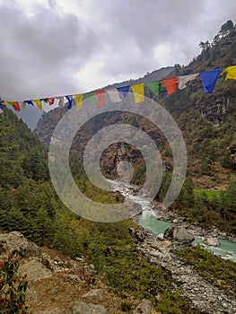 Dudh Koshi snow river in mountain valley and colorful prayer flags in Nepal