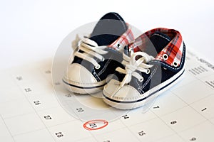 Due date in the calendar and detail of baby shoes photo