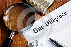 Due Diligence concept. Stack of documents and magnifying glass photo