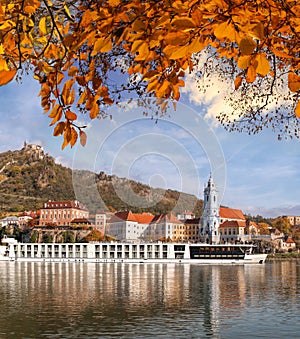 DUERNSTEIN CASTLE AND VILLAGE WITH BOAT ON DANUBE RIVER DURING AUTUMN TIME IN AUSTRIA