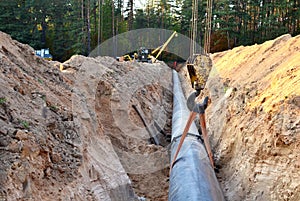 A Dug trench in the ground for the installation and installation of industrial gas and oil pipes. t.Crawler crane with side boom