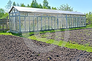 The dug-up beds and the greenhouse from glass frames on the seasonal dacha