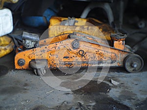 A dull and dirty yellow car jack. Jack up the car in the repair shop.