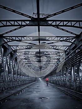 Dull Industrial bridge with cyclist in red