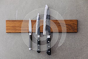 Dull Japanese kitchen knives stick on magnet cover with wood on concrete wall