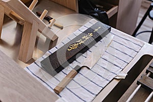 Dull and rustic Japanese kitchen knife waiting for sharpening on blue strip white fabric with sharpening equipment