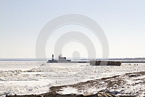 Visitors exploring The Crib on frozen Lake Superiorwith lighthouse on shipping pier in Duluth, Minnesota
