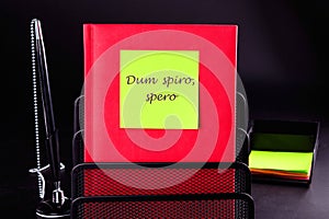 Dum Spiro Spero - latin phrase means While I Breath, I Hope. on a yellow sticker on a red notebook. Concept photo photo