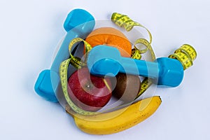 Dumbbell and apple, orange, banana, kiwi white background