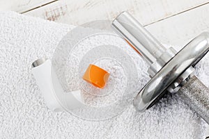 Dumbbell and asthma inhaler on white towel