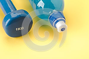 With dumbbell and bottle/blue dumbbell and bottle on a yellow background. Copy space. Top view