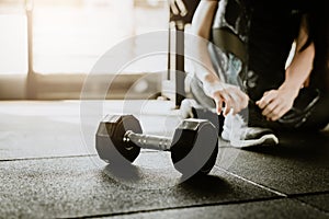 Dumbbell on the floor in gym with woman in background