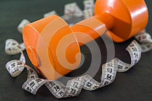 dumbbell and measuring tape on black. close-up