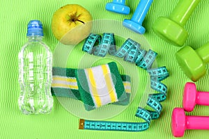 Dumbbells, apple, water bottle and cyan measure tape