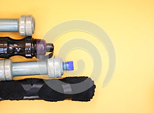 Dumbbells, bottle for water, dumbbells on a yellow background.Top view with copy space.