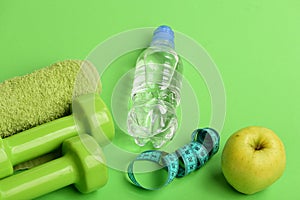 Dumbbells in bright green color, water bottle, measure tape, towel