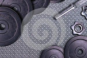Dumbbells on carbon background. Dumbbells and weights are lying on the floor in the gym. Barbell set and gym equipment. Metal