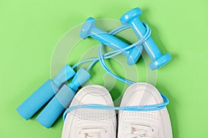 Dumbbells in cyan blue color on white trainers, top view