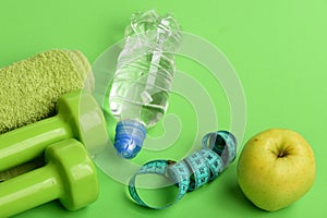 Dumbbells in green color, water bottle, measure tape and towel