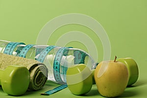 Dumbbells in green color, water bottle, measure tape, towel, fruit