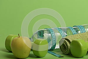 Dumbbells in green color, water bottle, measure tape, towel, fruit