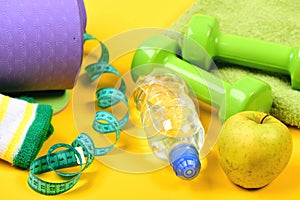 Dumbbells made of green plastic on yellow background