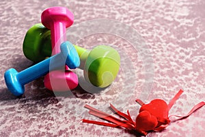 Dumbbells made of pink, green and cyan plastic near hearts