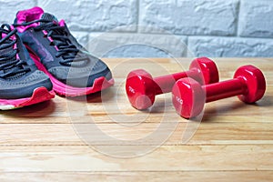 Dumbbells and sport shoes on wooden floor