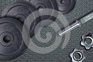 Dumbbells and weights are lying on the floor in the gym. Barbell set and gym equipment. Metal loads in the fitness club
