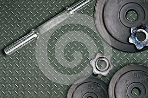 Dumbbells and weights are lying on the floor in the gym. Barbell set and gym equipment. Metal loads in the fitness club