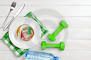 Dumbells and healthy food over wooden background