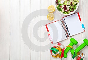 Dumbells, tape measure, healthy food and notepad for copy space