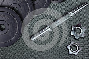 Dumbells and weights on the exercise mat. Fastening screws and barbells