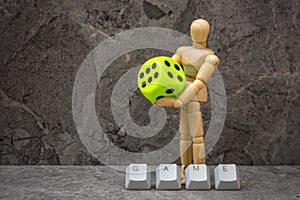 Dummy with a dice in hands next to computer keyboard keys arranged to spell GAME word photo