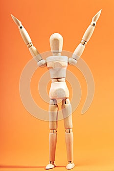 Dummy with raised arms celebrating success on an orange background