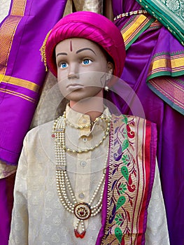 A dummy statue displayed showing a kid wearing traditional kurta and hat with jeawellery