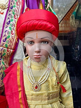 A dummy statue displayed showing a kid wearing traditional kurta and hat with jewellery