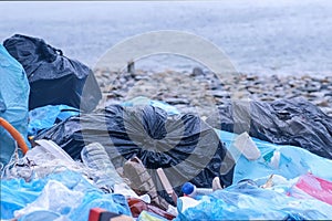 Dump garbage bags in nature on sea beach environmental pollution closeup.