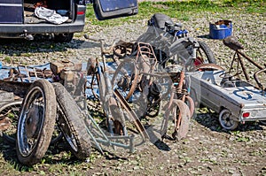 Dump the old broken rusty bicycles, motorcycles, toy cars, engines, tires and wheels with spokes in the open air on the ground